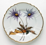 Thistle Dinner Plate Discerning hostesses and porcelain enthusiasts have long coveted Anna Weatherley\'s exquisite hand-painted porcelain tableware featuring butterflies, bugs and botanical images.  Anna Weatherley was born in Budapest, Hungary.  Her artistic nature was nurtured by an environment filled with beautiful architecture, furniture, marble, ironwork and artwork of her native country.  

Her father\'s death during the war left Anna and her mother destitute.  They eventually fled communist controlled Hungary for Australia, where Anna studied design and painting.  A trip to India resulted in Anna\'s falling in love with Indian handmade textiles.  By the Late 1970\'s her hand-painted and embroidered chiffon dresses were sold at Saks, Bloomingdales and Nordstroms, as well as privately to Elizabeth Taylor, Lady Bird Johnson, and the late Pamela Harrimon.  

When the end of the Cold War reopened Budapest, Anna returned to her beloved home city.  Her interests had turned to the works of the realistic 16th, 17th and 18th century botanical artists, and in Hungary she found artists talented enough to re-create the highly detailed, realistic style of these Romantic periods.  Anna breathed new life into Hungary\'s two-centuries-old tradition of hand-painted porcelain.  Anna\'s creative vision had again taken top retailers and consumers by storm by the late 1990\'s.  The editor of Vogue commissioned Anna Weatherly cachepots as a gift for England\'s late Princess Diane.  

As she ventures into the new century, Anna Weatherley again has ventured into new territory, offering consumers beautiful framed paintings on porcelain: butterflies, flowers and leaves, as well as watercolors on parchment paper.  These also have been enthusiastically received by a public which can never seem to get enough of Anna Weatherly.